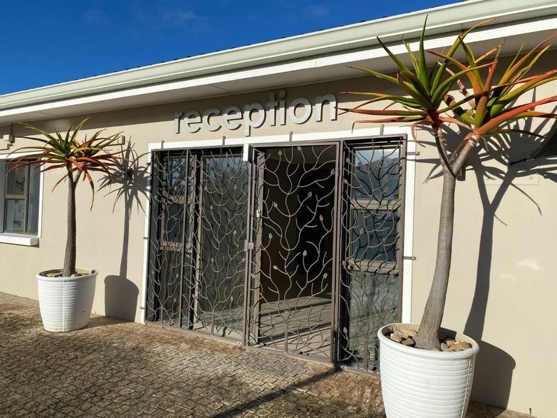 Front entrance of the property featuring a decorative security gate, paved approach, and clear signage for the reception area.