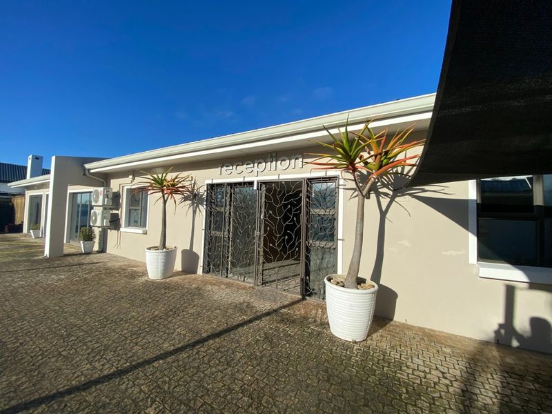 Front exterior view of the property entrance featuring paved driveway, security gate, and wall-mounted air conditioning units.