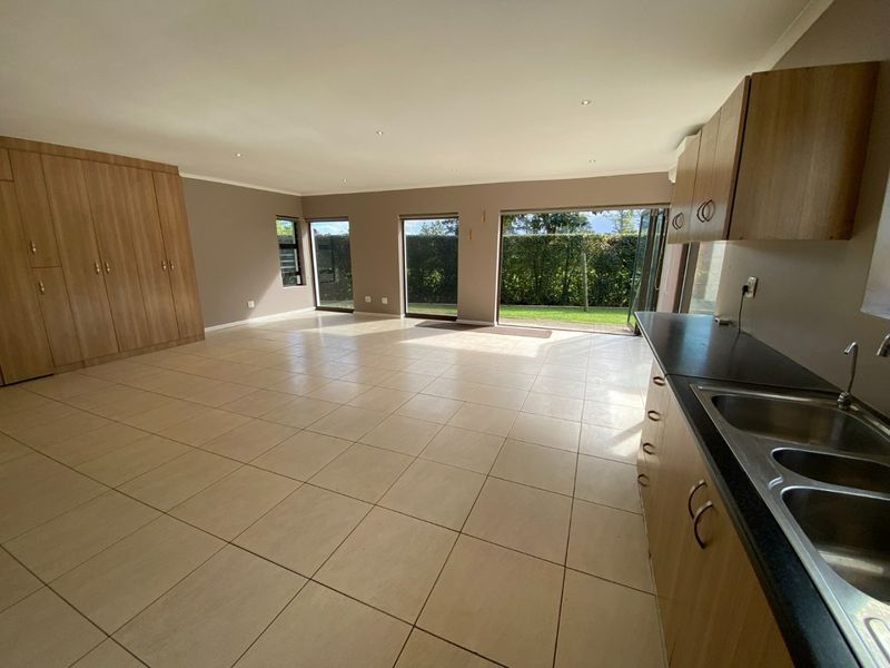 Spacious open-plan living area featuring tiled floors, built-in cabinetry, and large sliding doors providing seamless access to the garden.