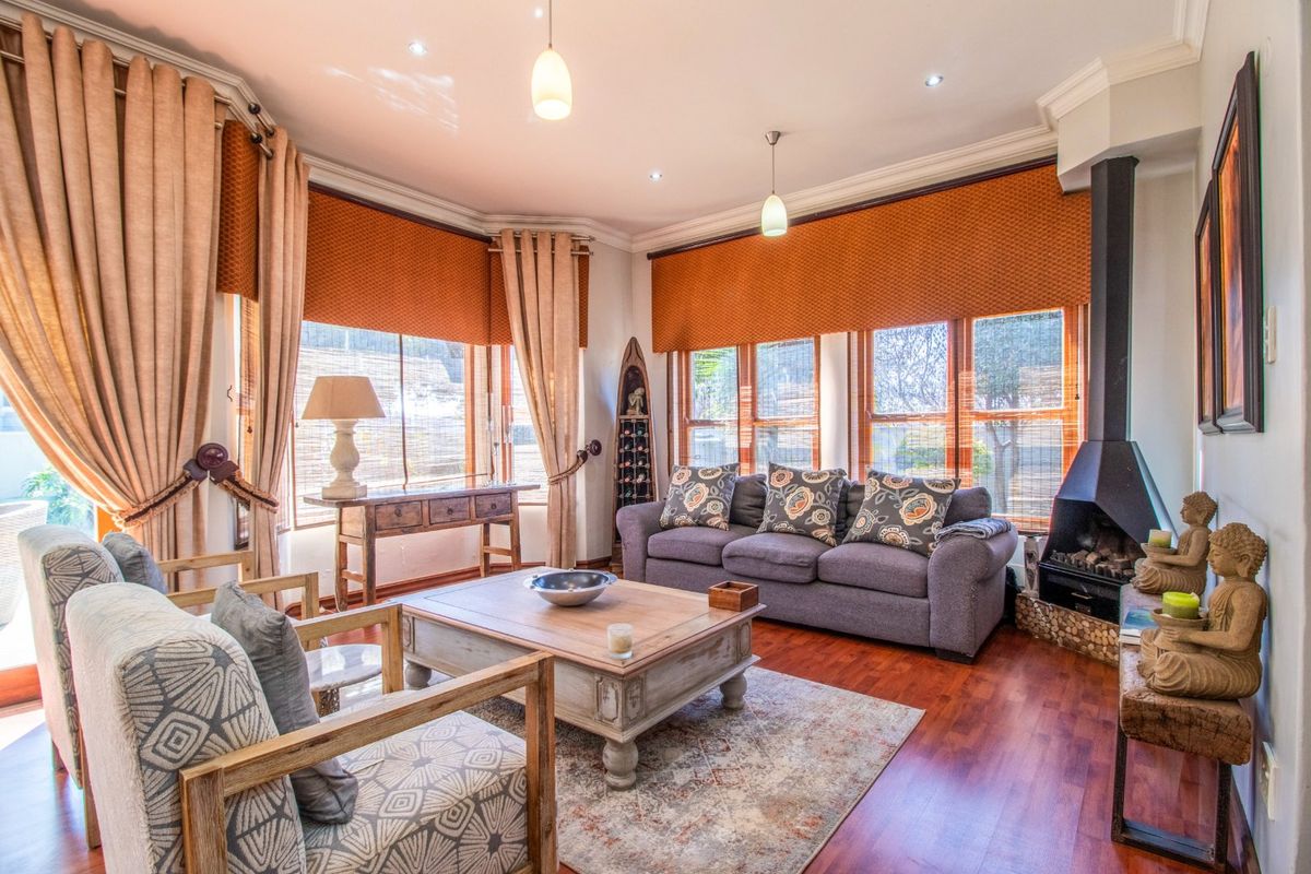 A well-lit living room featuring hardwood flooring, crown molding, and a modern freestanding fireplace, creating a warm and inviting atmosphere.