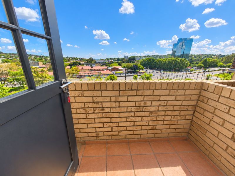 A private balcony featuring a brick parapet wall, tiled flooring, and an expansive urban view.
