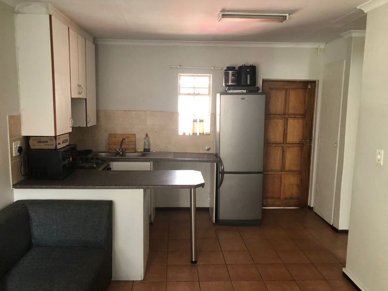 A functional kitchen featuring tiled flooring, laminate countertops, and built-in cabinetry, offering a practical layout with potential for modern cosmetic updates.