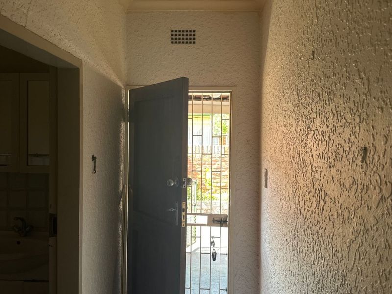 Entrance hallway featuring textured walls, tiled flooring, and a security gate, providing access to the interior living space.
