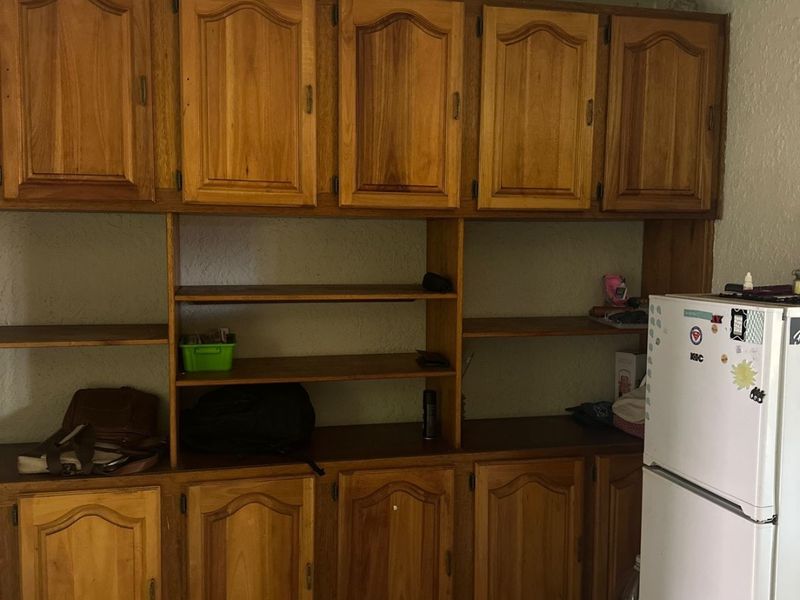 Kitchen area featuring extensive built-in wooden cabinetry and tiled flooring, offering significant storage space with a dated aesthetic.