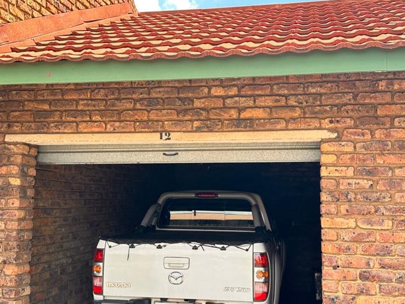 A single-car garage featuring exposed brickwork and a traditional tiled roof, providing secure off-street parking.