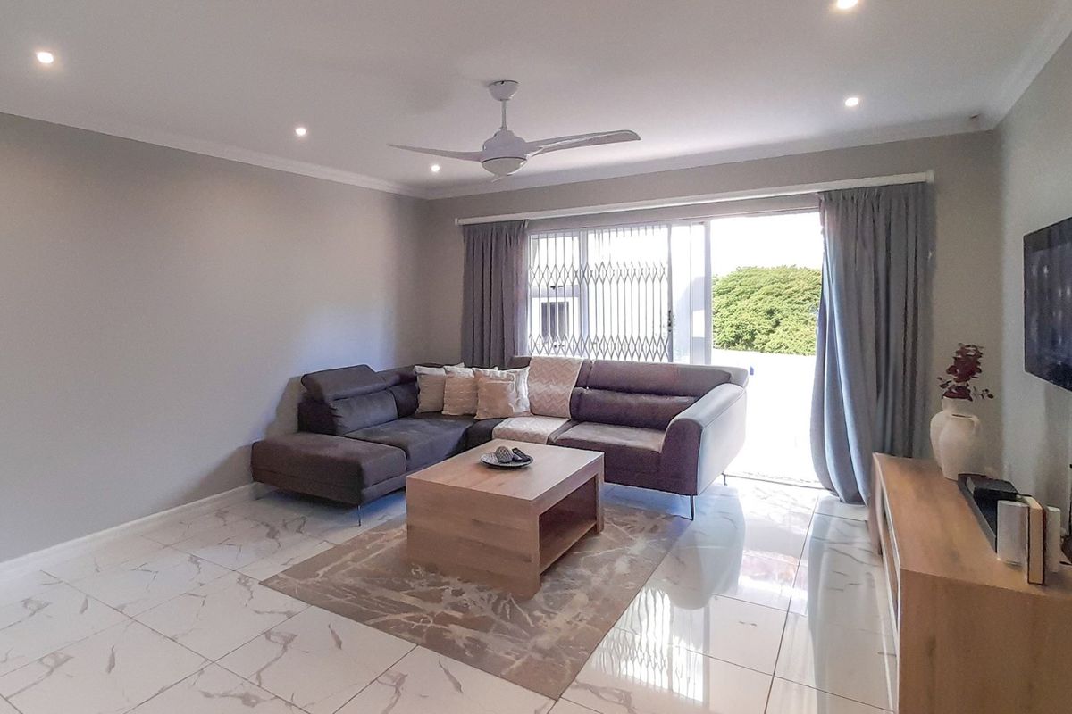 A bright living room featuring polished marble-look floor tiles, recessed downlights, a ceiling fan, and a sliding glass door leading to an outdoor area.