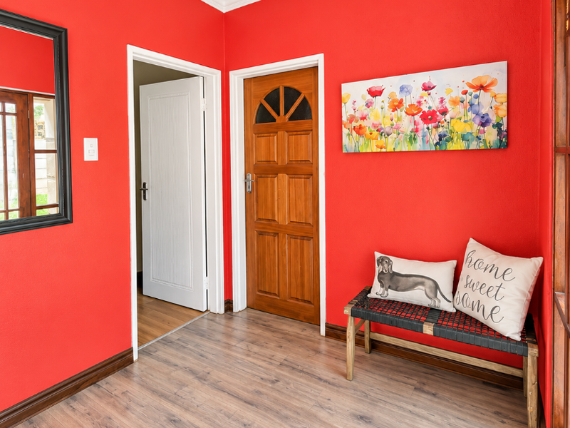 Bright entrance hall featuring laminate flooring, crown molding, and a solid wooden door with decorative glass paneling.