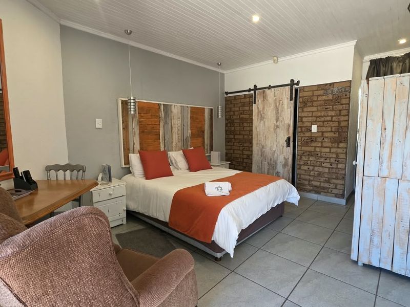 A well-maintained bedroom featuring exposed brick accents, a sliding barn door, tiled flooring, and a beadboard ceiling, creating a rustic and inviting atmosphere.