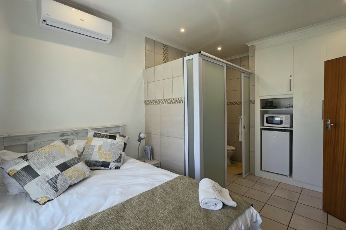 A well-maintained bedroom featuring tiled flooring, built-in cabinetry, a split-system air conditioner, and an integrated en-suite bathroom partition.