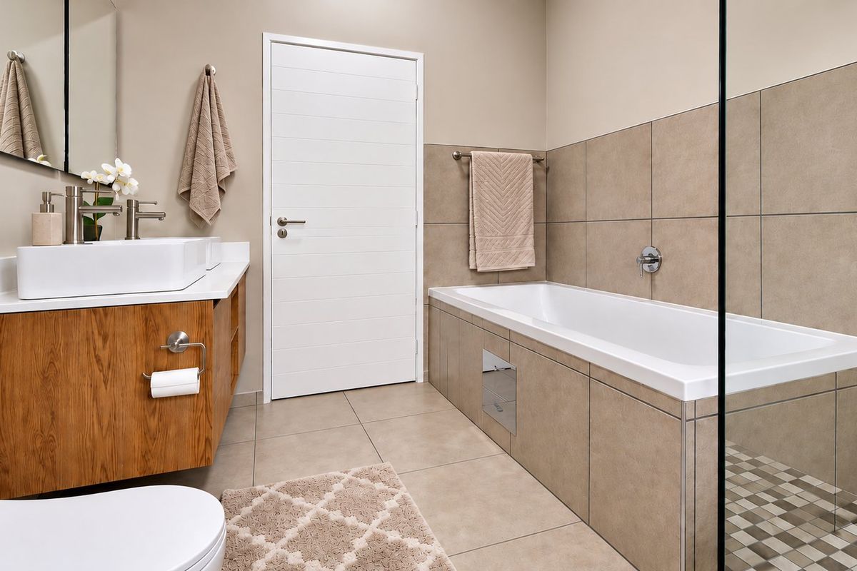 Modern bathroom featuring a vessel sink on a wood-finish vanity, a tiled built-in bathtub, and a glass-enclosed shower area with neutral finishes.