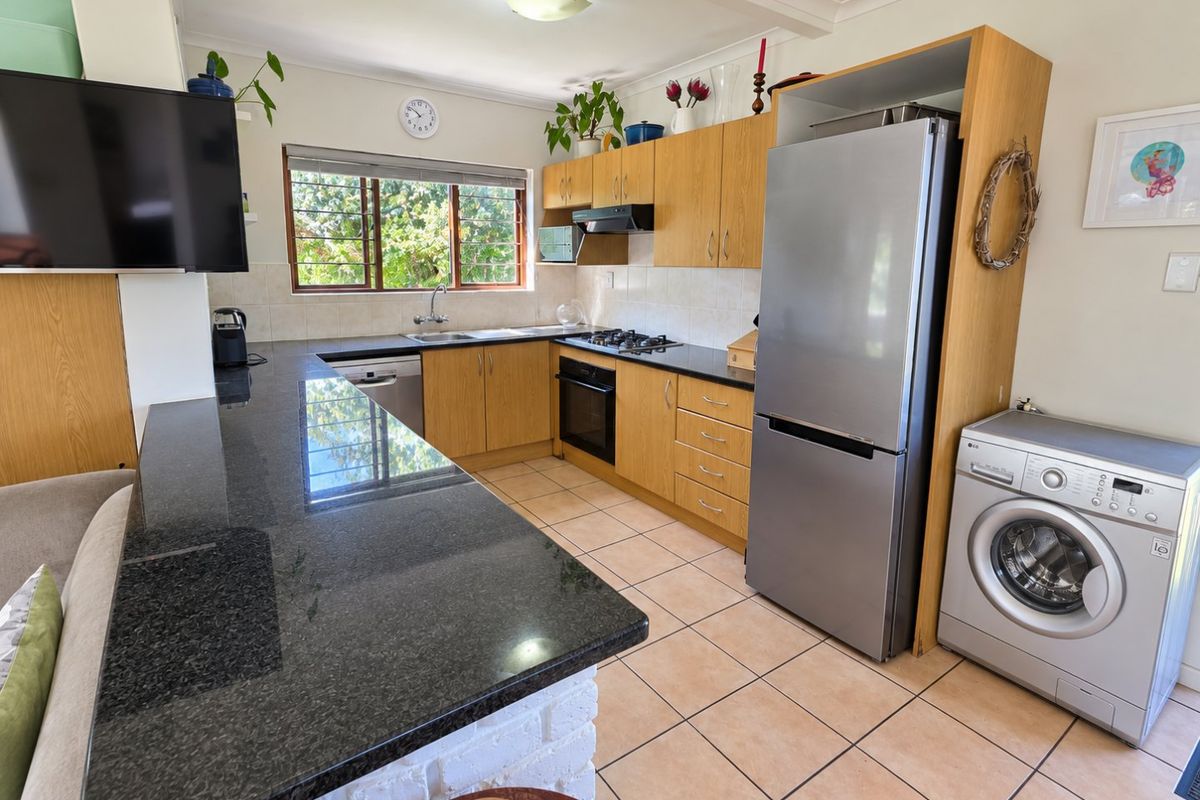 Functional kitchen featuring granite countertops, built-in cabinetry, gas hob, oven, and integrated space for laundry appliances, offering a practical layout for daily use.