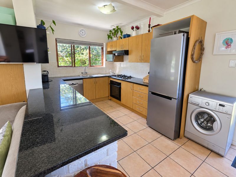 Functional kitchen featuring granite countertops, built-in cabinetry, gas hob, oven, and integrated space for laundry appliances, offering a practical layout for daily use.