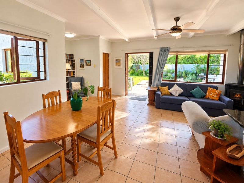 Spacious open-plan living and dining area featuring tiled floors, a wood-burning fireplace, ceiling fan, and direct access to the rear garden.
