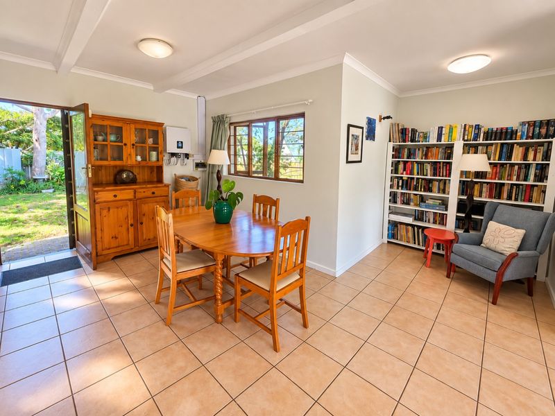 A bright dining area featuring tiled flooring, built-in shelving, and direct access to the garden through a glass-paneled door.