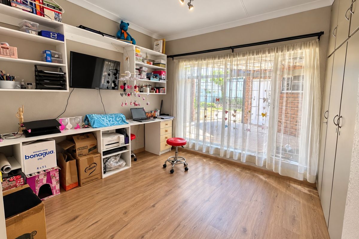 A bedroom featuring laminate flooring, built-in cabinetry, and a built-in desk with shelving, offering functional storage and workspace with natural light.