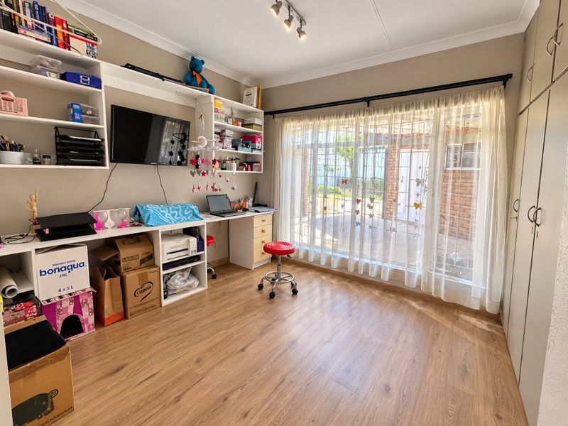 A bedroom featuring laminate flooring, built-in cabinetry, and a built-in desk with shelving, offering functional storage and workspace with natural light.