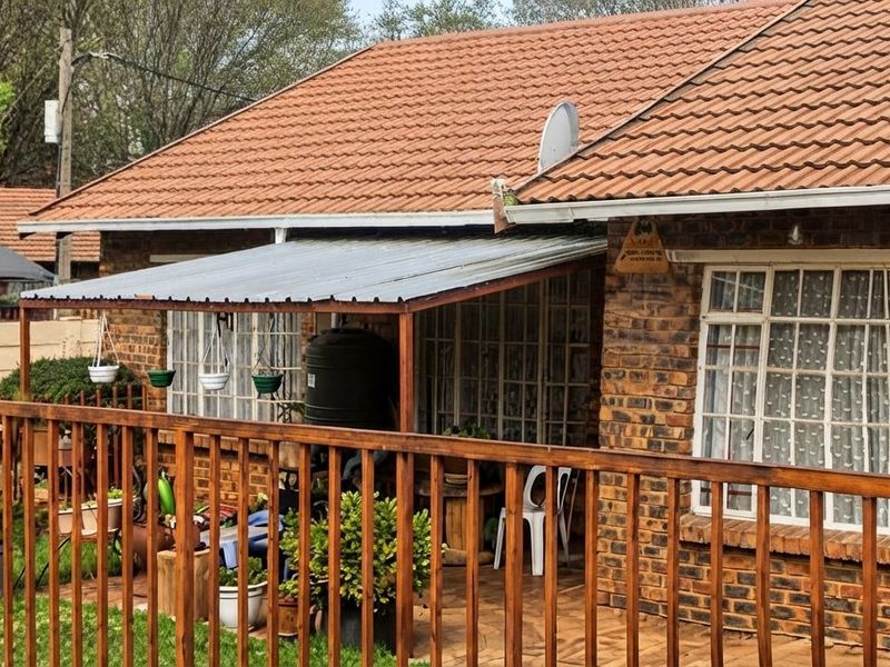 A rear view of the house featuring a brick facade, tiled roof, and a covered patio area with a timber balustrade.