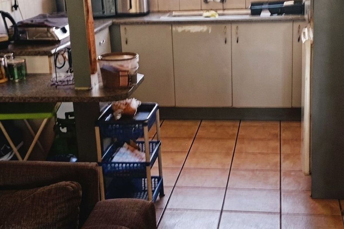 A functional kitchen featuring laminate countertops, built-in cabinetry, and tiled flooring, offering a practical layout with a window overlooking the exterior.
