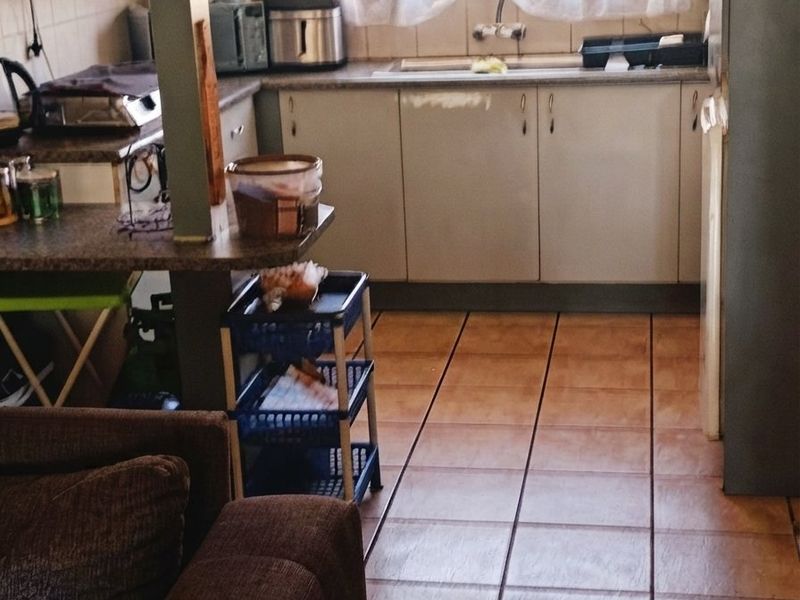 A functional kitchen featuring laminate countertops, built-in cabinetry, and tiled flooring, offering a practical layout with a window overlooking the exterior.