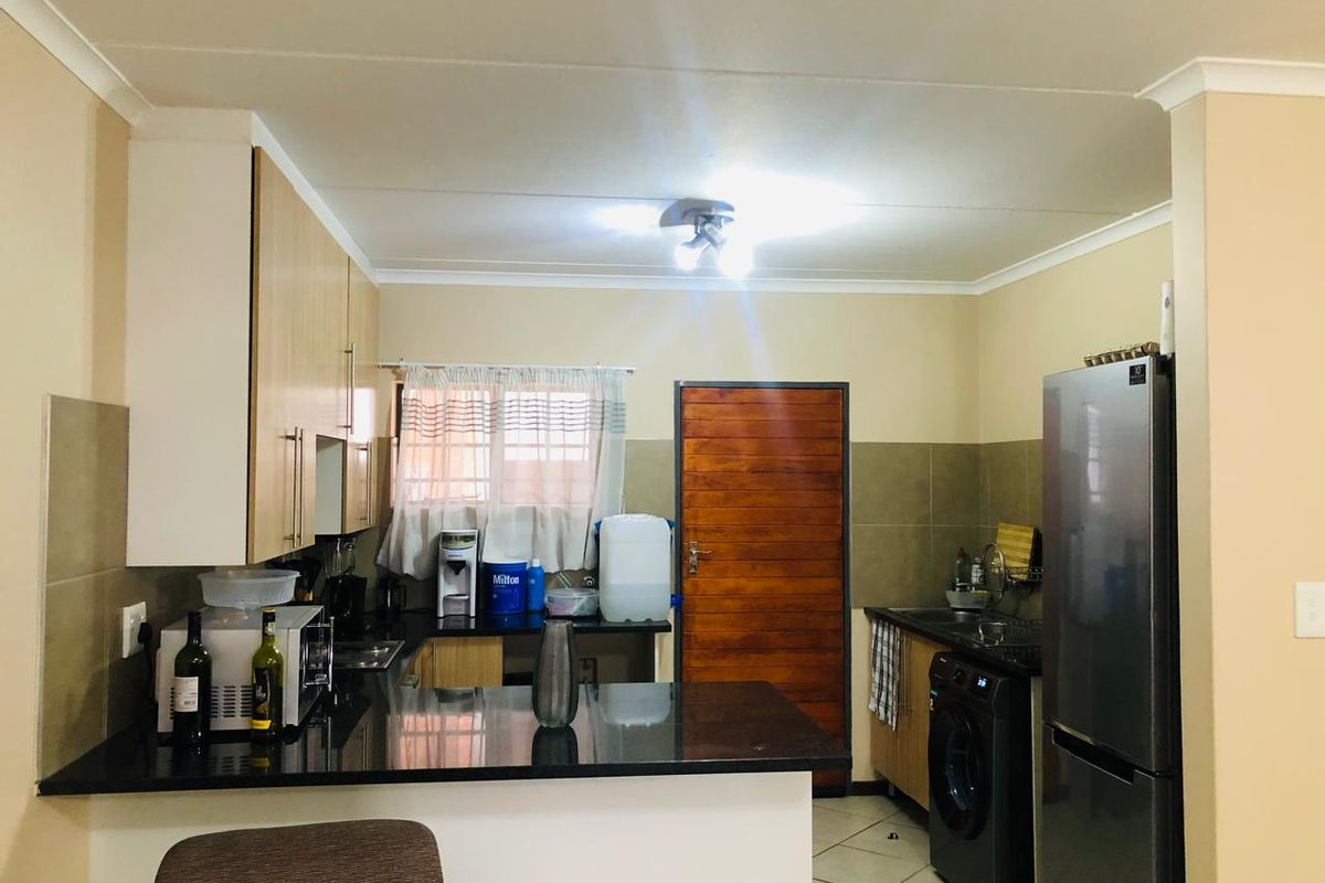 A functional kitchen featuring granite countertops, tiled backsplash, and ample cabinetry, providing a practical workspace with direct access to an exterior door.