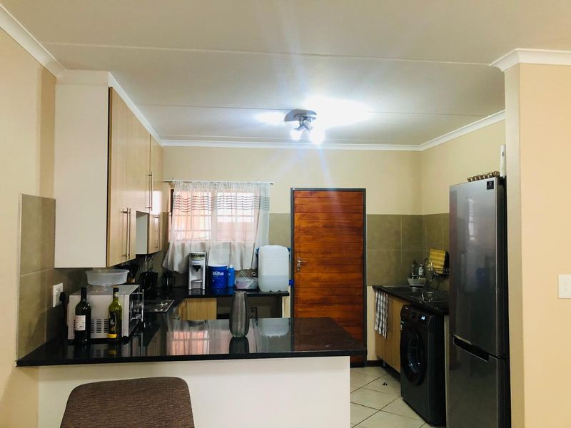 A functional kitchen featuring granite countertops, tiled backsplash, and ample cabinetry, providing a practical workspace with direct access to an exterior door.