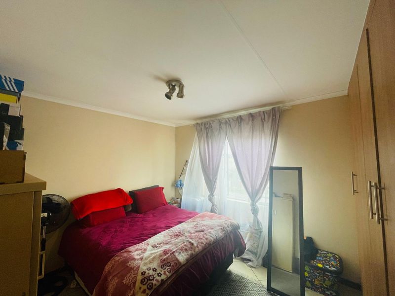 A functional bedroom featuring a built-in wardrobe, neutral wall finishes, and a ceiling-mounted spotlight fixture.