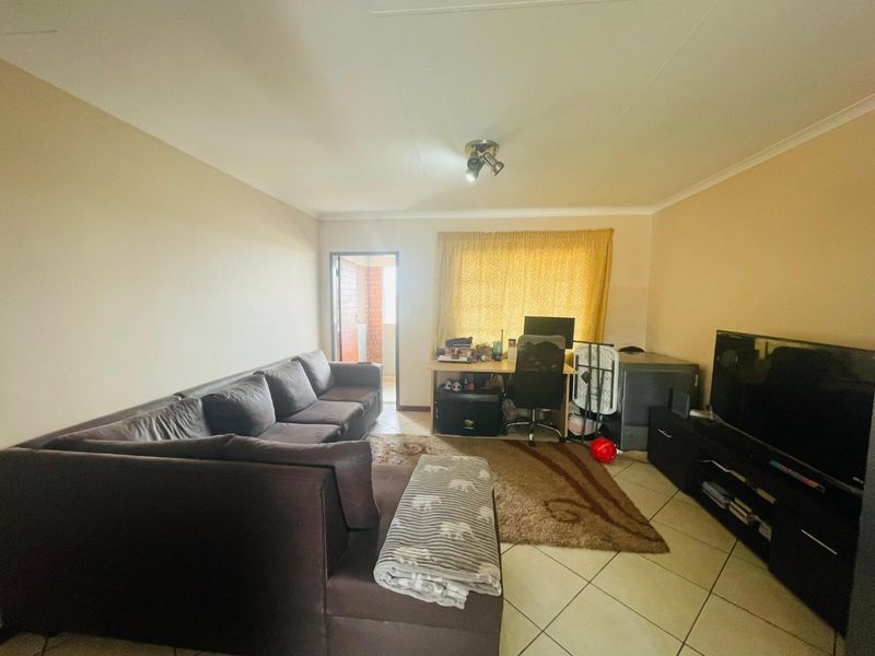 A functional living room featuring tiled flooring and direct access to an outdoor balcony area.