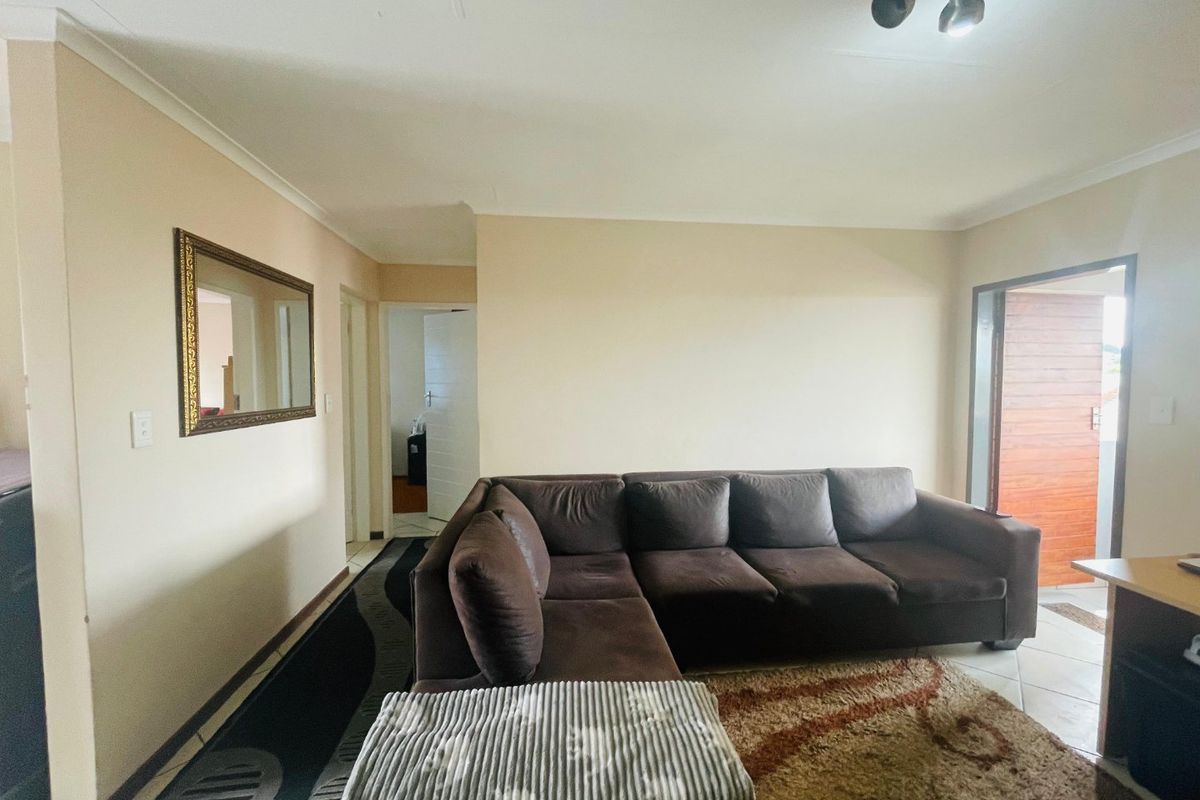 A living room area featuring tiled flooring, coving, and a spotlight fixture, providing access to adjacent rooms and an external entrance.