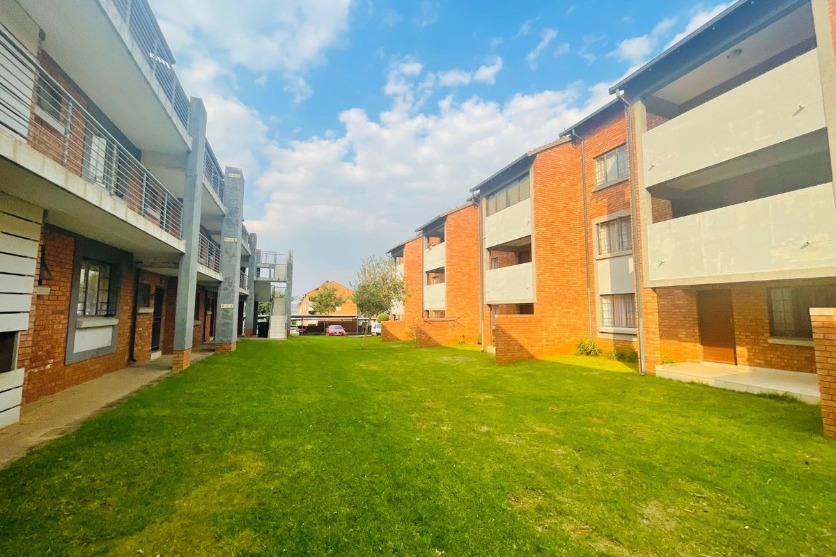 View of the apartment complex exterior featuring brick facades, communal lawn space, and private balconies.