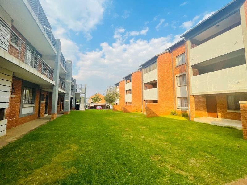 View of the apartment complex exterior featuring brick facades, communal lawn space, and private balconies.