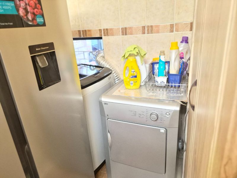 A compact laundry area featuring a tiled splashback and dedicated space for laundry appliances.