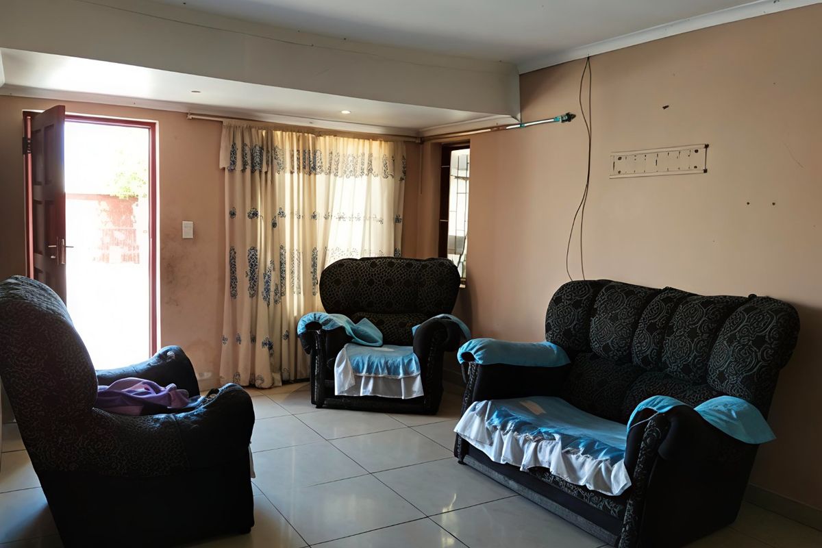 A living room area featuring tiled flooring and direct access to the exterior, requiring cosmetic updates to the walls and finishes.