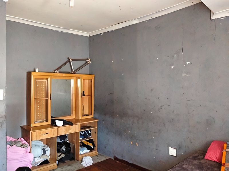 A bedroom featuring dark grey walls with visible surface damage and wear, requiring cosmetic attention and repainting.