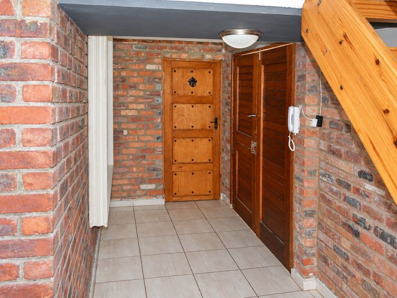 An entrance hall featuring exposed brick walls, tiled flooring, and a wooden staircase, providing a rustic and characterful welcome to the home.