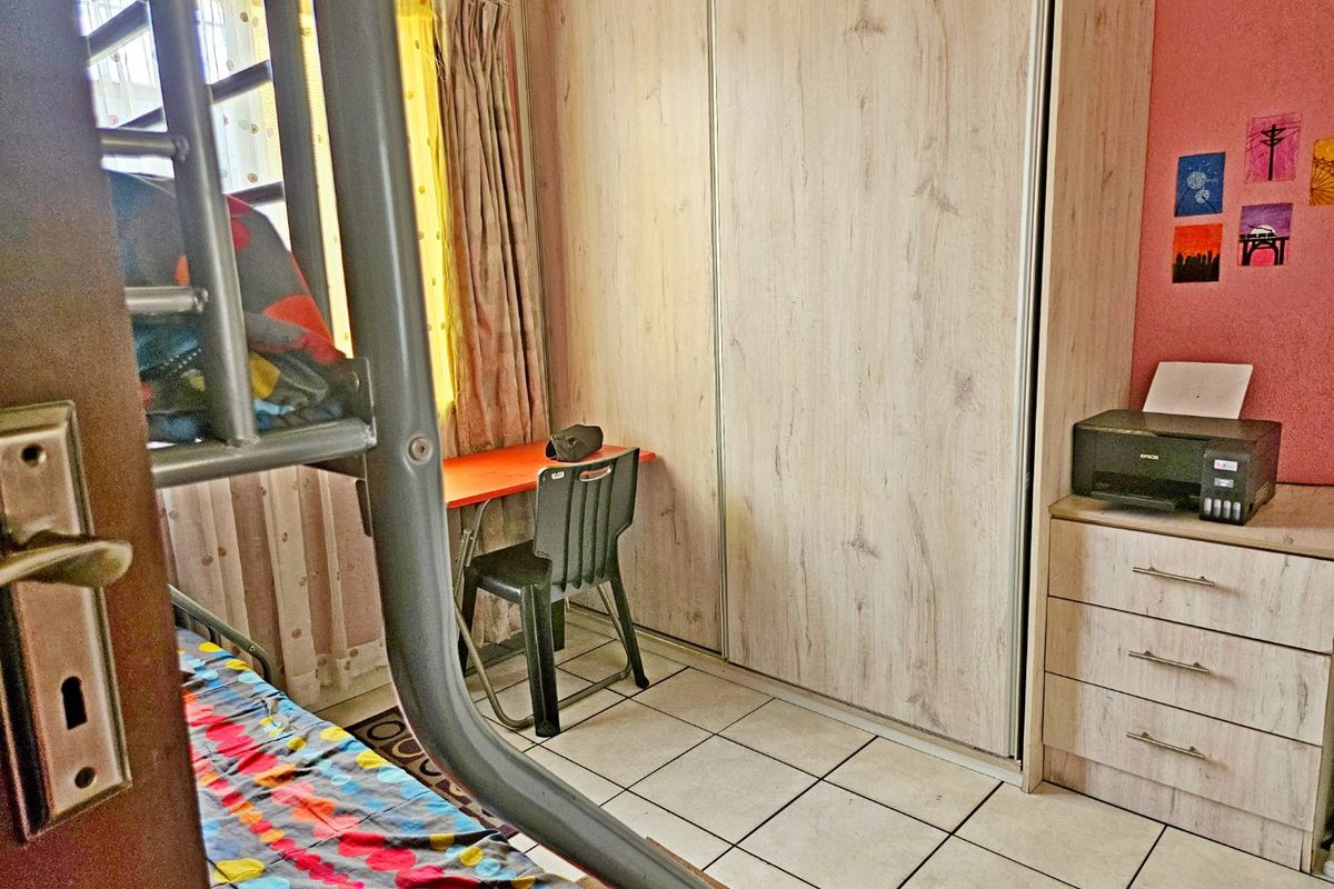 A functional bedroom featuring tiled flooring and a built-in wardrobe with light wood-grain finish doors.