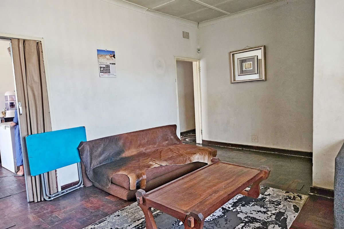 A living room featuring parquet flooring and ceiling tiles, presenting a dated aesthetic that would benefit from cosmetic updates.