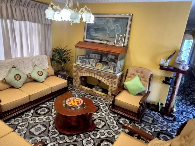 A traditional living room featuring a brick-faced feature wall, decorative ceiling cornice, and a central chandelier, offering a classic layout for family relaxation.