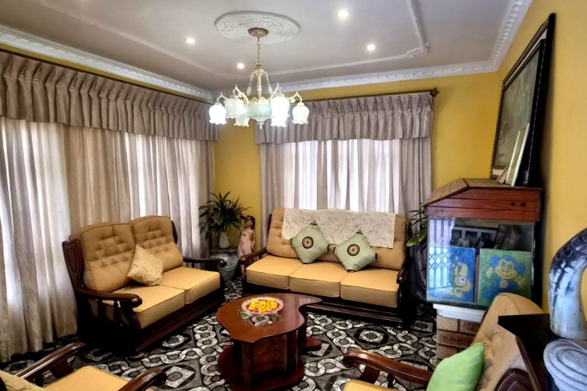 A living room featuring decorative ceiling cornicing, a central ceiling rose with a chandelier, and recessed downlights, providing a traditional aesthetic.
