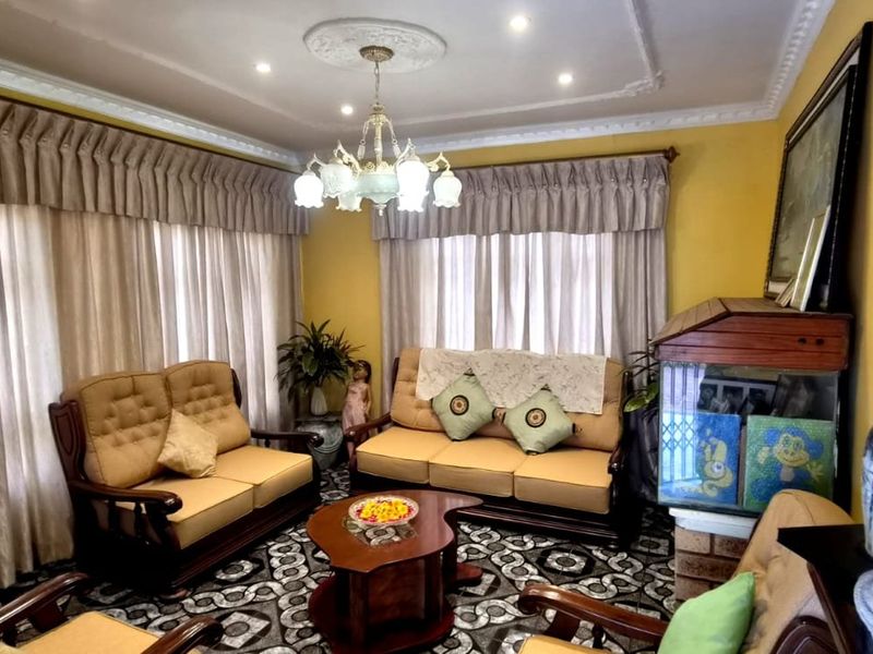 A living room featuring decorative ceiling cornicing, a central ceiling rose with a chandelier, and recessed downlights, providing a traditional aesthetic.