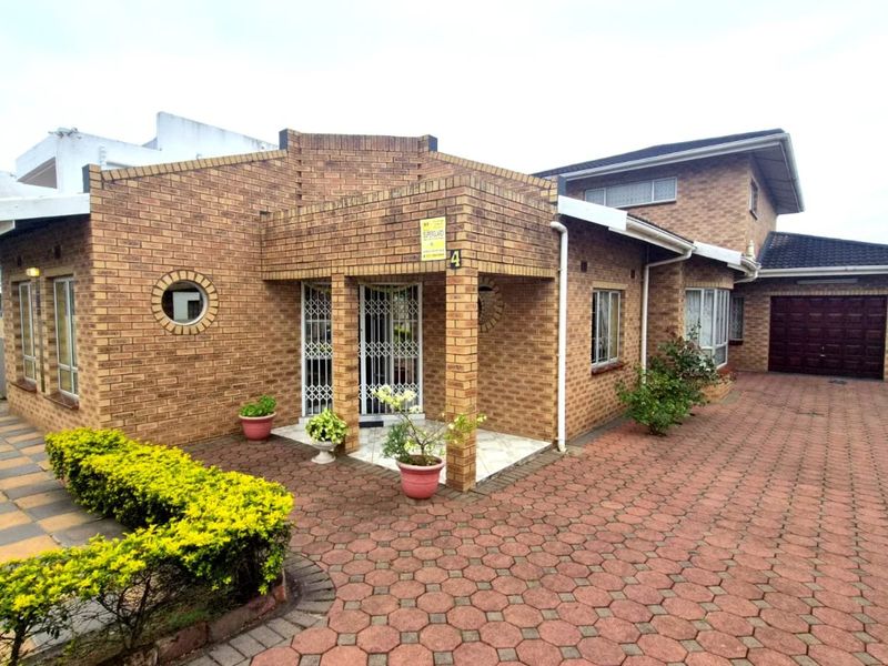 A well-maintained face brick house featuring a paved driveway, covered entrance porch, and an integrated garage.
