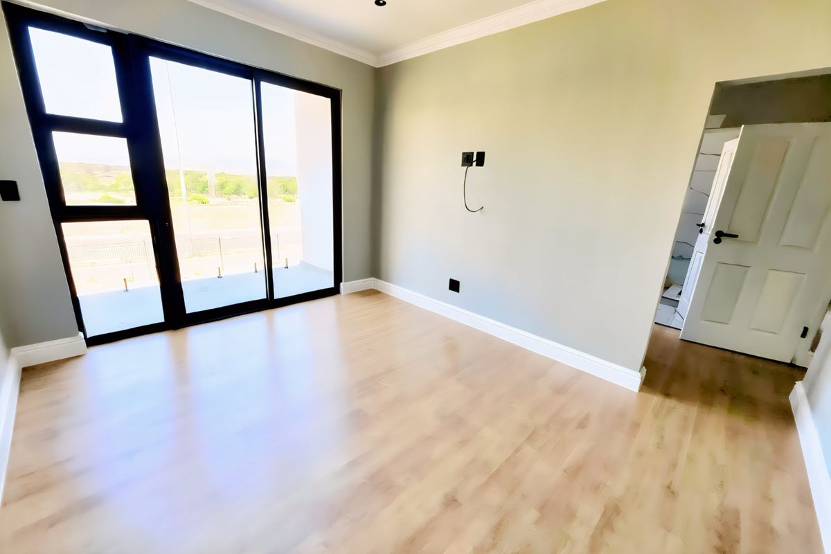 A bright, empty bedroom featuring modern laminate flooring, recessed lighting, and large sliding glass doors leading to an outdoor area.