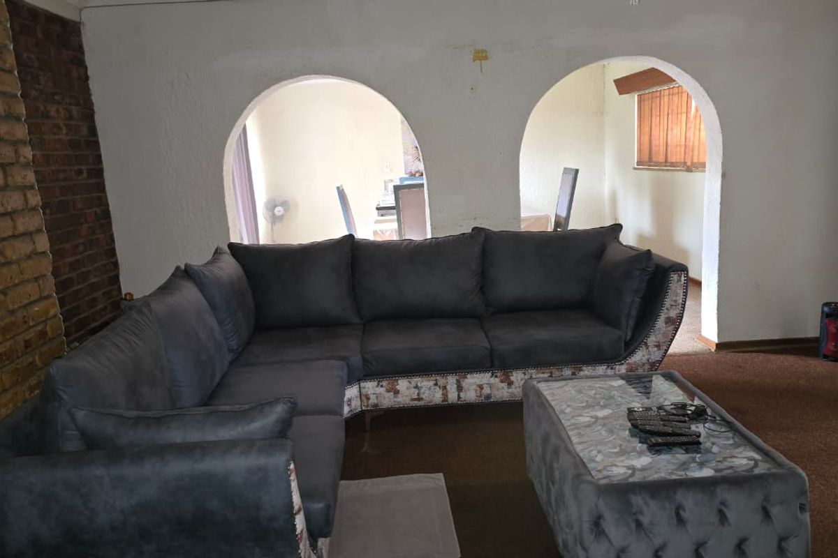 Living room featuring an exposed brick accent wall and distinctive arched openings leading to an adjacent space, with carpet flooring throughout.