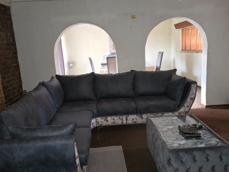 Living room featuring an exposed brick accent wall and distinctive arched openings leading to an adjacent space, with carpet flooring throughout.