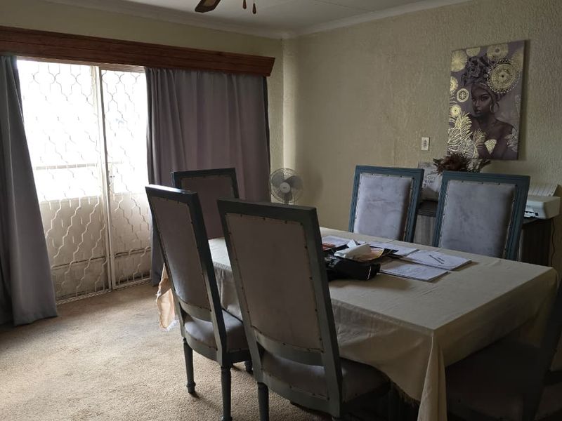 A dining room featuring carpeted flooring, a ceiling fan, and a sliding glass door with an integrated security gate leading to the exterior.