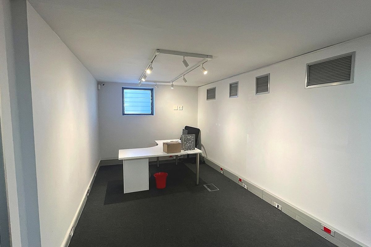 A functional commercial office space featuring track lighting, carpeted flooring, integrated air conditioning vents, and floor trunking for electrical connectivity.