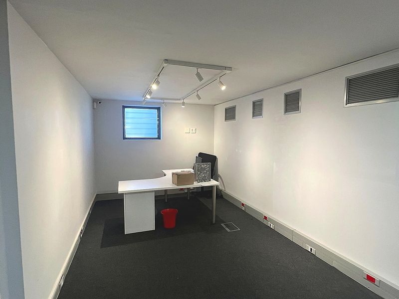 A functional commercial office space featuring track lighting, carpeted flooring, integrated air conditioning vents, and floor trunking for electrical connectivity.