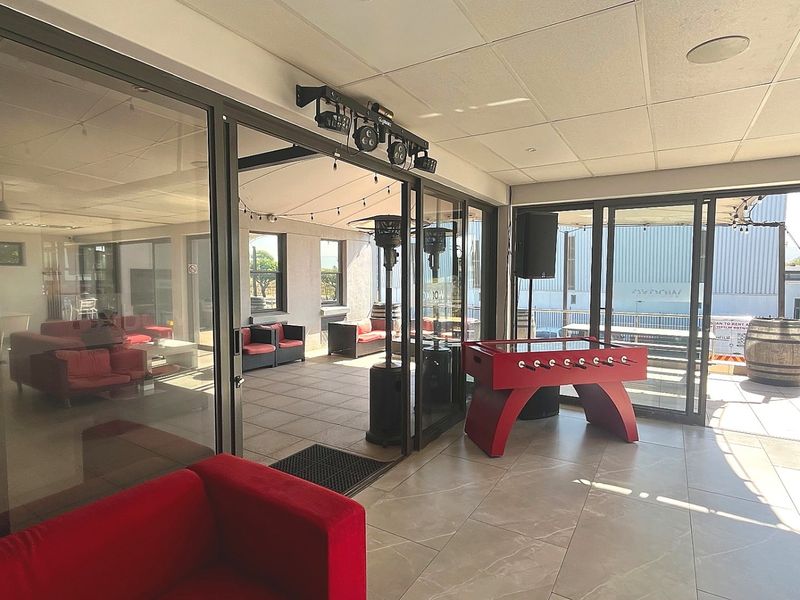 Spacious covered patio area featuring large sliding glass doors, modern tiled flooring, and integrated ceiling lighting, suitable for commercial entertainment or social gatherings.