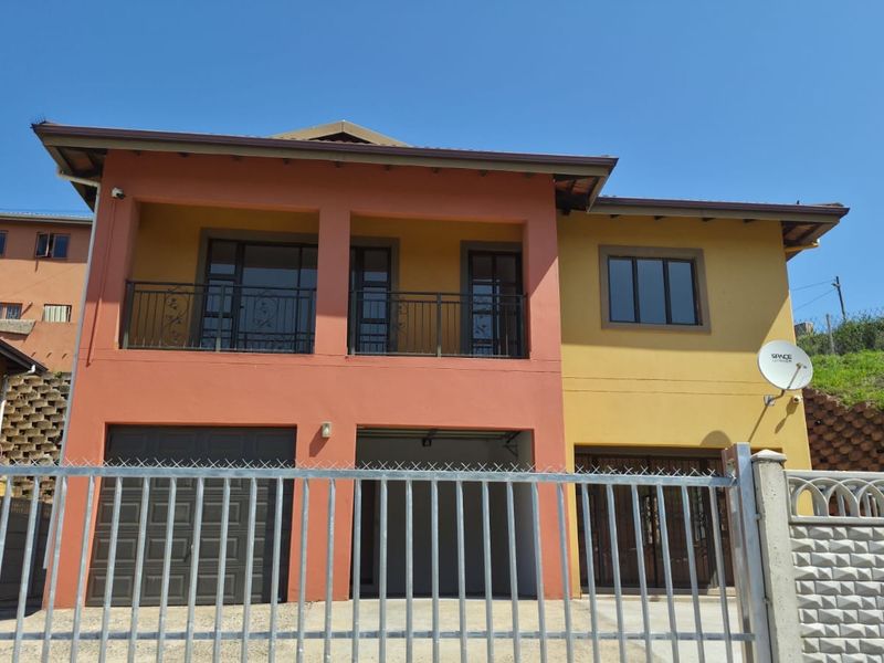 Two-story residential property featuring a double garage, upper-level balcony, and secure metal perimeter fencing.