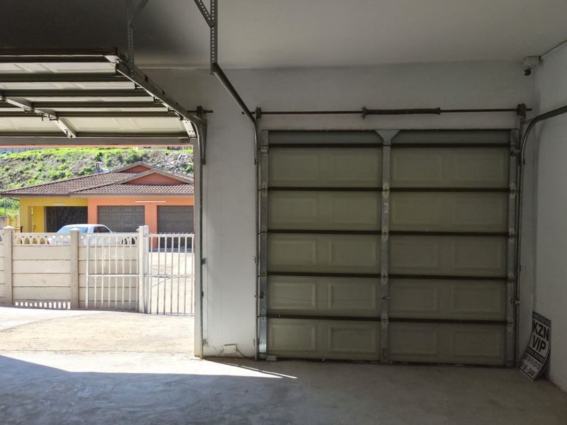 A spacious, empty double garage featuring concrete flooring, a sectional garage door, and secure window access.