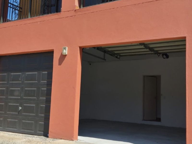 A double garage with a concrete driveway and an upper-level balcony featuring decorative wrought iron railings.
